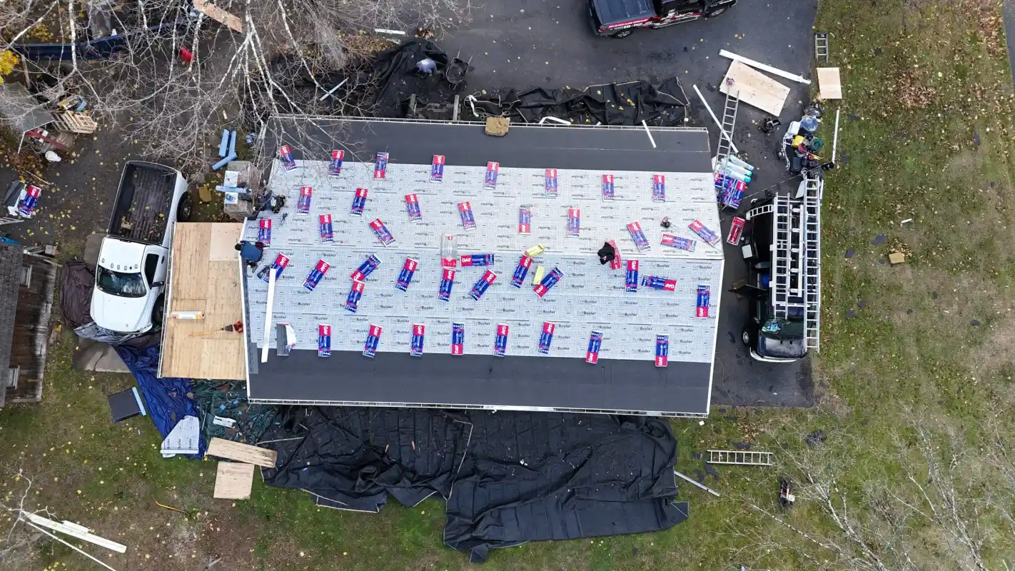 Aerial view of workers installing a new roof with shingles and materials