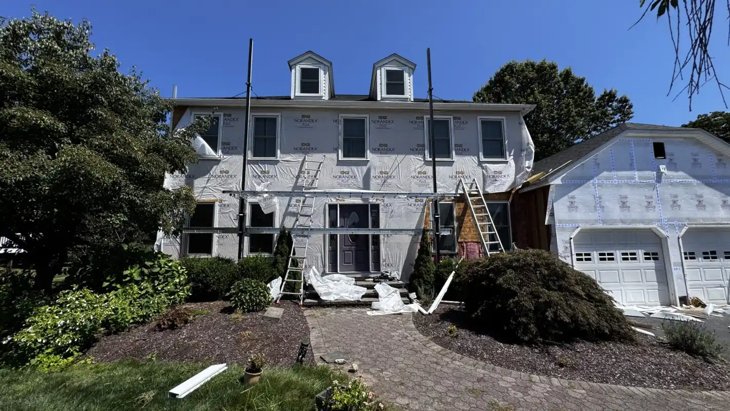 House under construction with white house wrap and ladders