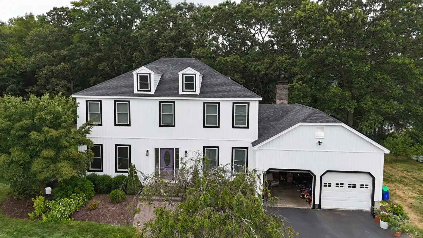 White farmhouse with black trim and a new dark shingle roof